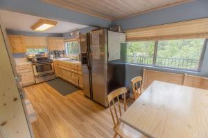 a kitchen with a stainless steel refrigerator and a table at Near Yosemite Bass Lake Cabin with Hot Tub, Lake View, Pet Friendly in Bass Lake