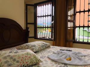 a bed with two towels on it with windows at Hotel casa gustadora in Cali +12 photos