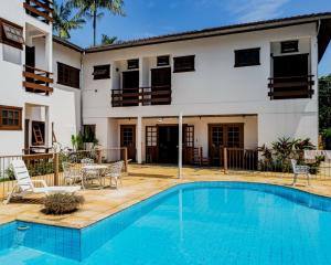 a villa with a swimming pool and a house at Pousada Ubatuba Villa Tupi in Ubatuba