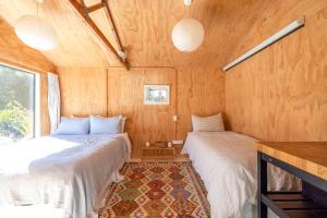 deux lits dans une chambre aux murs en bois dans l'établissement Tranquility Cottage, Oneroa - Be My Guest Waiheke, à Waiheke Island