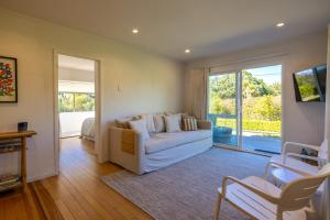 un salon avec un canapé et une porte coulissante en verre dans l'établissement Tranquility Cottage, Oneroa - Be My Guest Waiheke, à Waiheke Island