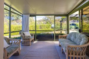 un porche grillagé avec des chaises et des fenêtres dans l'établissement Tranquility Cottage, Oneroa - Be My Guest Waiheke, à Waiheke Island