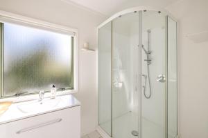 une salle de bain blanche avec une douche et un lavabo dans l'établissement Tranquility Cottage, Oneroa - Be My Guest Waiheke, à Waiheke Island 26 autres photos