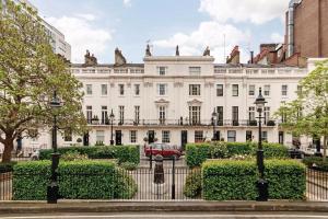 a woman standing in front of a white building at Secluded Modern Private Apartment by Buckingham Palace in London