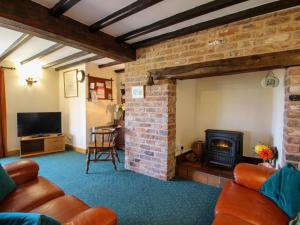 a living room with leather furniture and a brick fireplace at White Cottage in Hopton Wafers