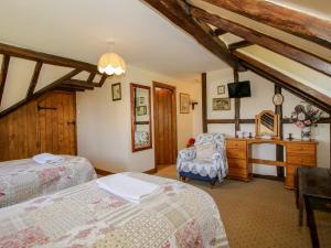 a bedroom with two beds and a dresser with a tv at White Cottage in Hopton Wafers