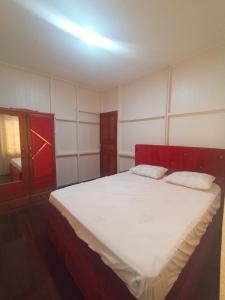a bedroom with a large white bed with a red door at Kar appartements in Paramaribo