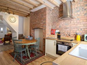a kitchen with a table and a brick wall at Derwen House in Llangollen