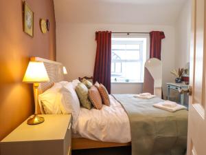 a bedroom with a bed with a lamp and a window at Derwen House in Llangollen
