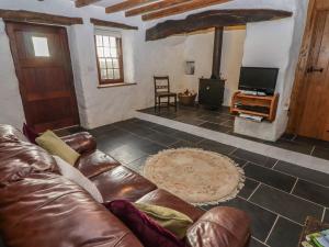 a living room with a leather couch and a wood stove at Panteurig Cottage in Goodwick