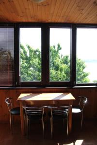 a wooden table and chairs in a room with windows at Два дома на берегу Лимана in Vapnyarka