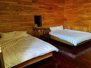 two beds in a room with wooden walls at Homestay Nhà Mộc in Da Lat
