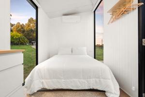 a bedroom with a bed and a large window at Glorious Escape by Tiny Away in Jindivick