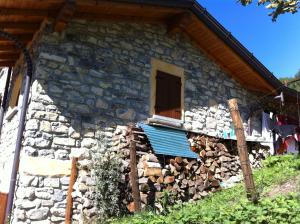 a stone house with a blue roof and a pile of fire wood at Agriturismo Il Talento Nella Quiete in Castiglione dʼIntelvi