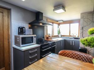 eine Küche mit Herd und Mikrowelle in der Unterkunft Coupling Cottage in Belper