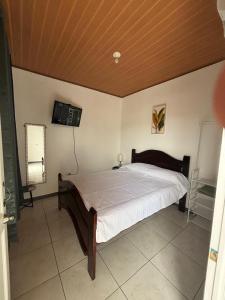 Un dormitorio con una cama y un televisor en la pared. en Depa Koral, en Puerto Limón
