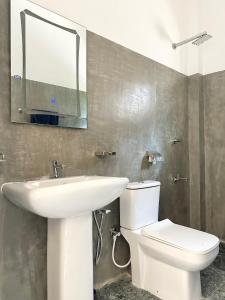 a bathroom with a sink and a toilet and a mirror at Tobby Home Stay in Ahangama