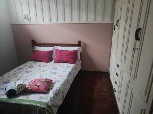 a small bedroom with a bed with pink pillows at Pousada Aleha Quarto Casal Rosé in Montes Claros