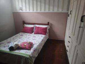 a small bedroom with a bed with pink pillows at Pousada Aleha Quarto Casal Rosé in Montes Claros