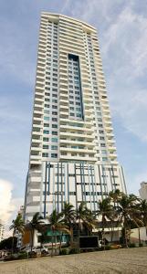 a tall building with palm trees in front of it at Apartamento en Edificio Palmetto Beach frente a la Playa in Cartagena de Indias