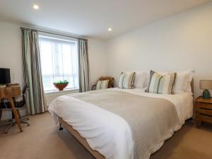a white bedroom with a large bed and a window at 4 Ocean Gate in Newquay