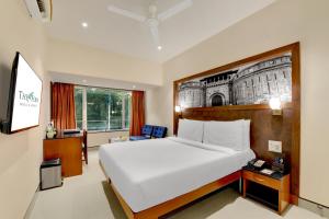 a bedroom with a large white bed and a window at The Fern Residency Woodland, Pune in Pune
