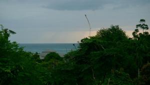 een uitzicht op de oceaan vanuit een bos van bomen bij Le Grand Bleu in Koh Samui 