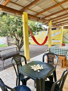 a patio with a table and chairs and a hammock at Casa Amarela in Presidente Figueiredo