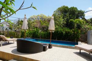 una piscina con due ombrelloni accanto a una piscina di Karang Buncing Lembongan a Nusa Lembongan
