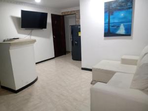 a living room with a white couch and a tv at Casa Turística Samanta in Buga
