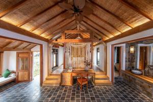 a room with a wooden ceiling with a table and chairs at Hang Mua Ecolodge in Ninh Binh
