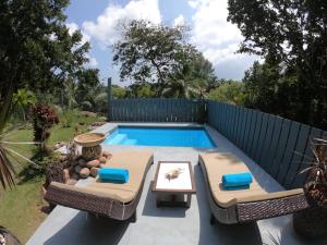 a swimming pool with two chairs and a table at Villa Tamanu in Praslin