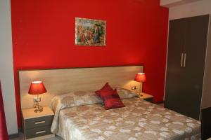 - une chambre dotée d'un mur rouge avec un lit et deux lampes dans l'établissement Gallery B&b Milazzo, à Milazzo