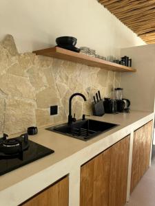 a kitchen with a sink and a stone wall at Ecstatic Villa, heart of Uluwatu in Uluwatu