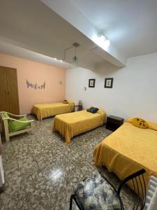 a room with three beds with yellow sheets at Departamento La Paz in La Falda