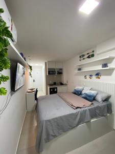 a white bedroom with a bed and a kitchen at Flat na beira-mar de Tamandaré in Tamandaré