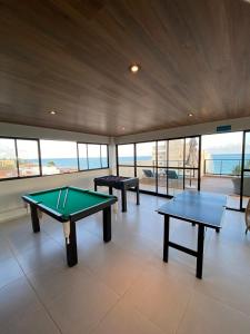 a room with two ping pong tables and the ocean at Flat na beira-mar de Tamandaré in Tamandaré