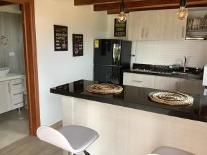 a kitchen with a counter with two chairs and a refrigerator at Cabaña Assyria in Zapatoca +6 photos