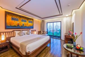 a bedroom with a large bed and a large window at Fivitel Hoi An Hotel in Hoi An