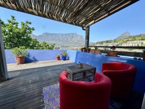 a deck with two chairs and a table and mountains at Casa Finchette rooftop apartment with panoramic views of Table Mountain in Cape Town