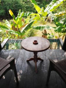 a table and two chairs on a wooden deck at Charming dark lodge in river in Weligama