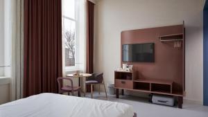 a hotel room with a bed and a table and a tv at Conscious Hotel Oudegracht in Utrecht