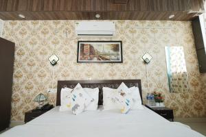 a bedroom with a bed with white sheets and pillows at Swagat Guest House in Dehradun