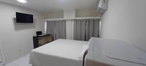 a white bedroom with a bed and a tv at AP Central VIP 02 in Campina Grande