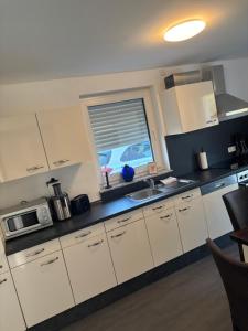 a kitchen with white cabinets and a sink and a window at Baierrefreies Apartment Stielzchen Steinbeck in Recke +4 photos