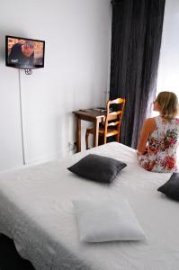 une femme assise sur un grand lit dans l'établissement Logis Hotel du Midi, à Salon-de-Provence