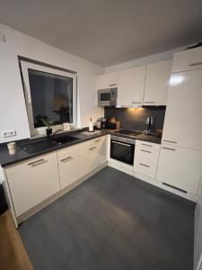 a kitchen with white cabinets and a sink and a window at Apartment Tilda Steinbeck in Recke
