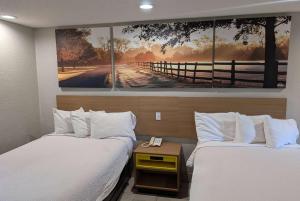 Dos camas en una habitación con un cuadro en la pared. en Days Inn by Wyndham Arcadia Louisiana, en Arcadia
