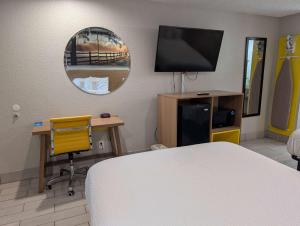 Una habitación con una cama, un escritorio y un televisor. en Days Inn by Wyndham Arcadia Louisiana, en Arcadia