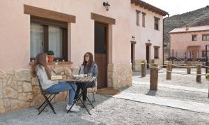 dos mujeres sentadas en una mesa frente a un edificio en Senda del Cabrerizo, en Albarracín